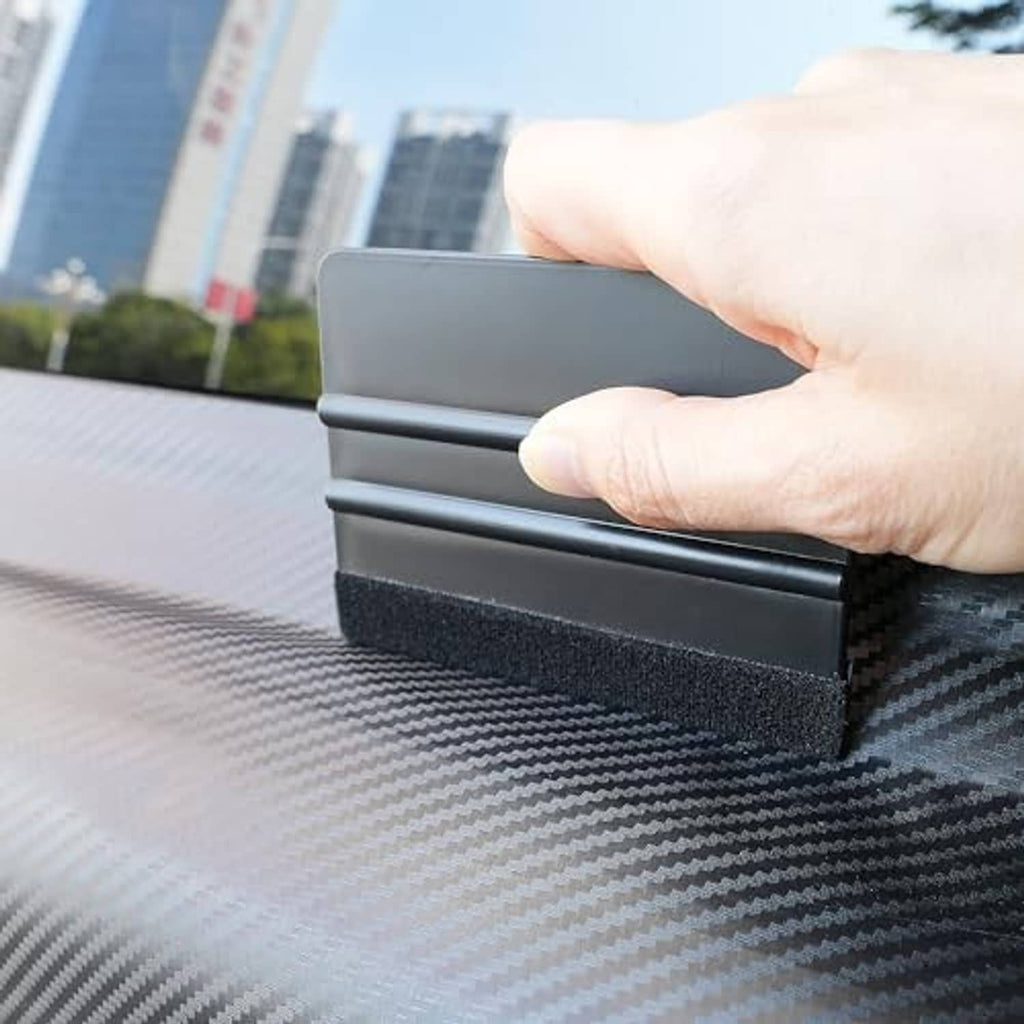 Hand smoothing window film using a gray plastic squeegee with felt edge