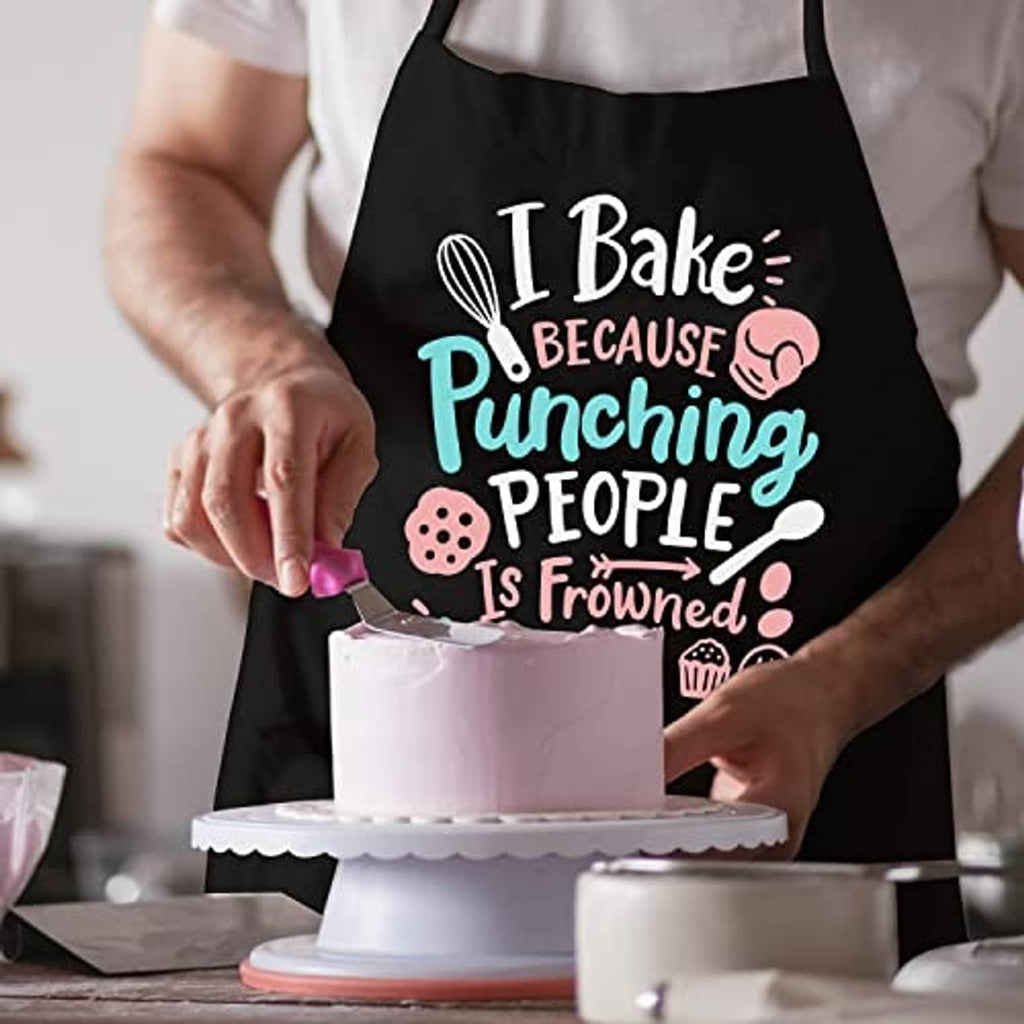 Black baking apron with 'I Bake' slogan while frosting a cake on a stand