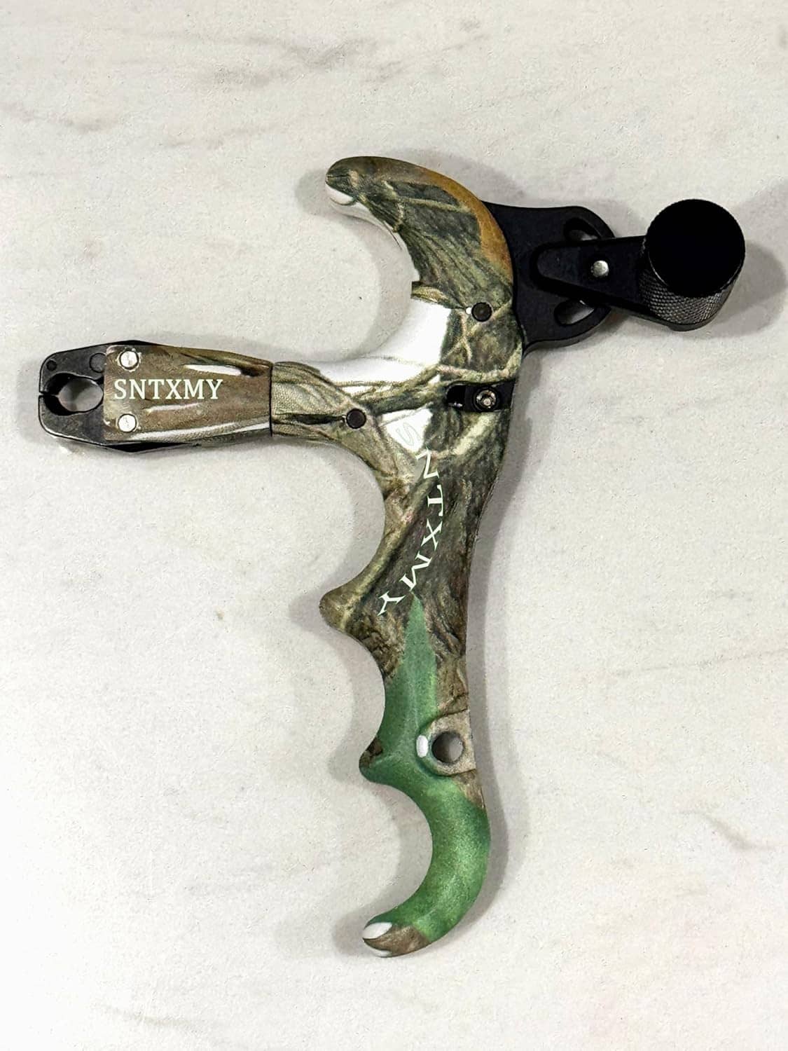 Camouflage thumb bow release showing metal U-shaped safety and black end knob.