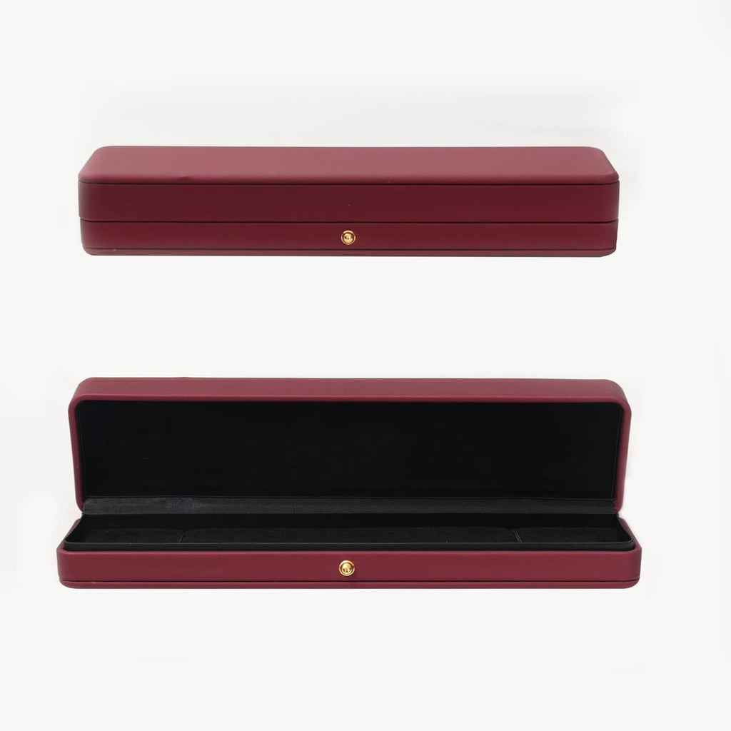 Red necklace box open to show black velvet-lined tray and gold clasp