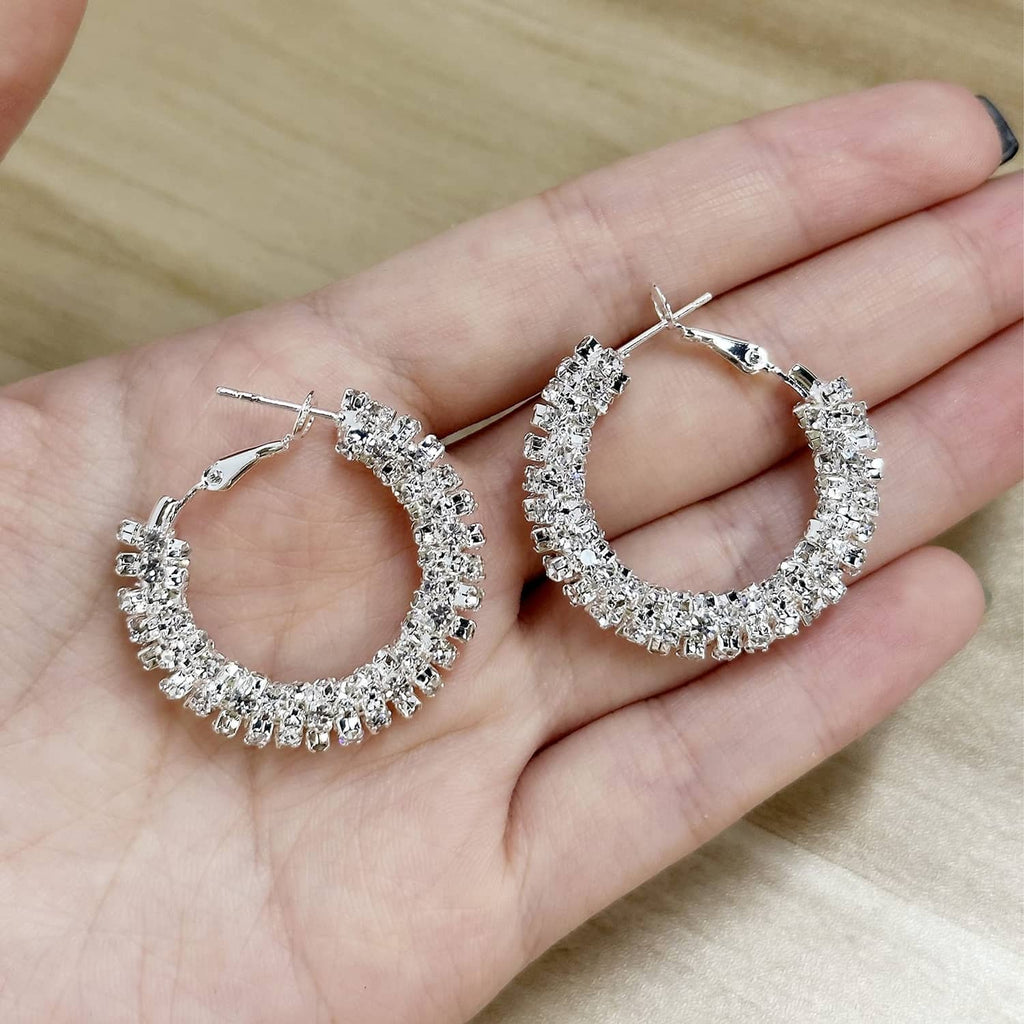 Silver-toned hoop earrings with faceted stone texture, shown held in a hand