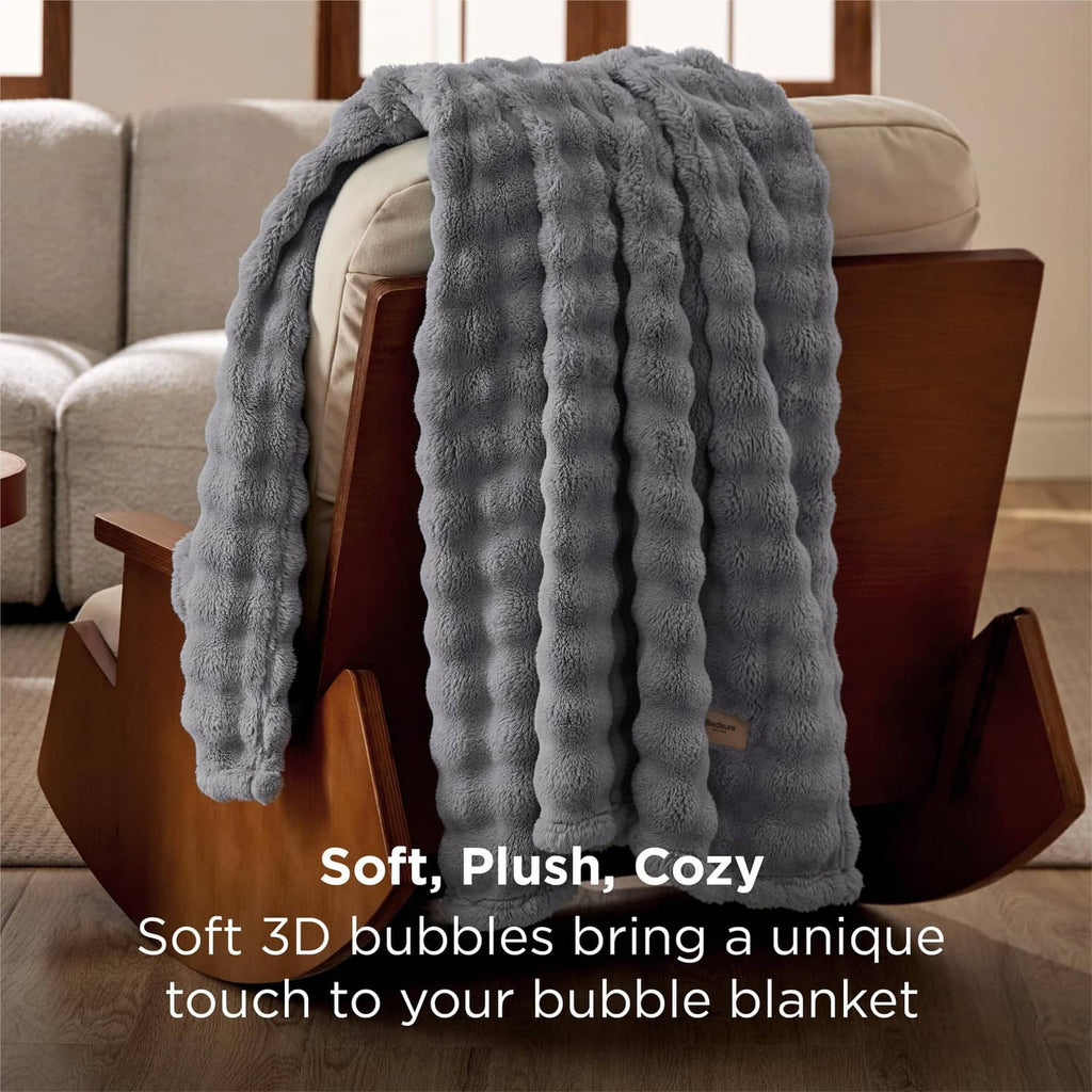 Gray bubble fleece throw blanket with ribbed 3D bubble pattern, folded on a sofa
