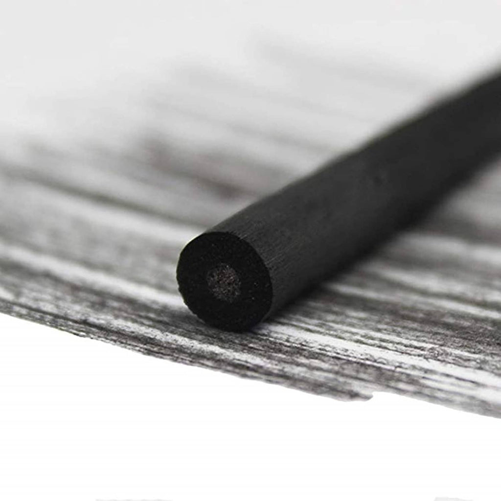 Single dark charcoal stick on a sketch surface, round end visible