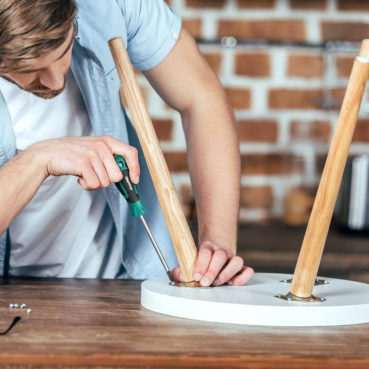 Person using teal-handled precision screwdriver to install screws on a board