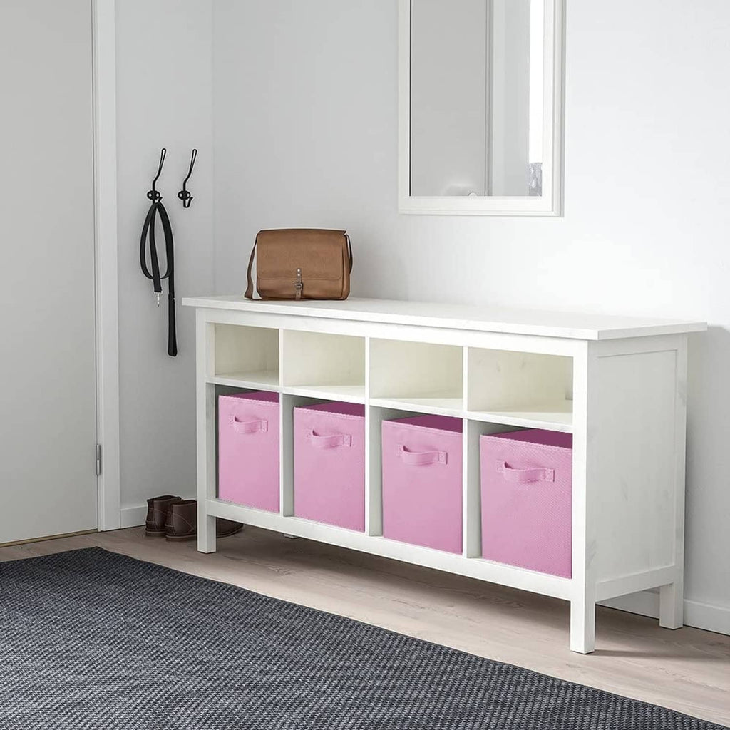 Pink foldable storage bins with front handles in a white cabinet cubby