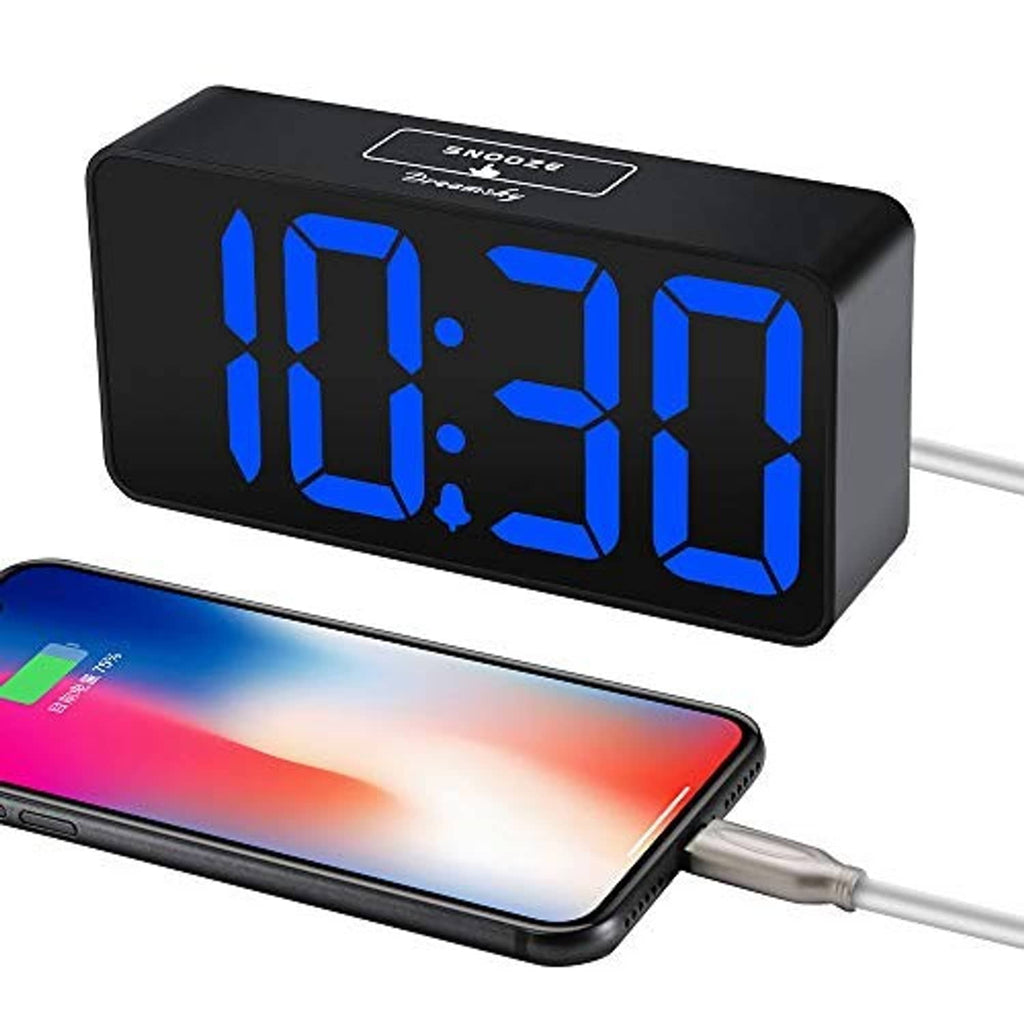 Digital alarm clock with large blue LED digits and charging cable connected to phone