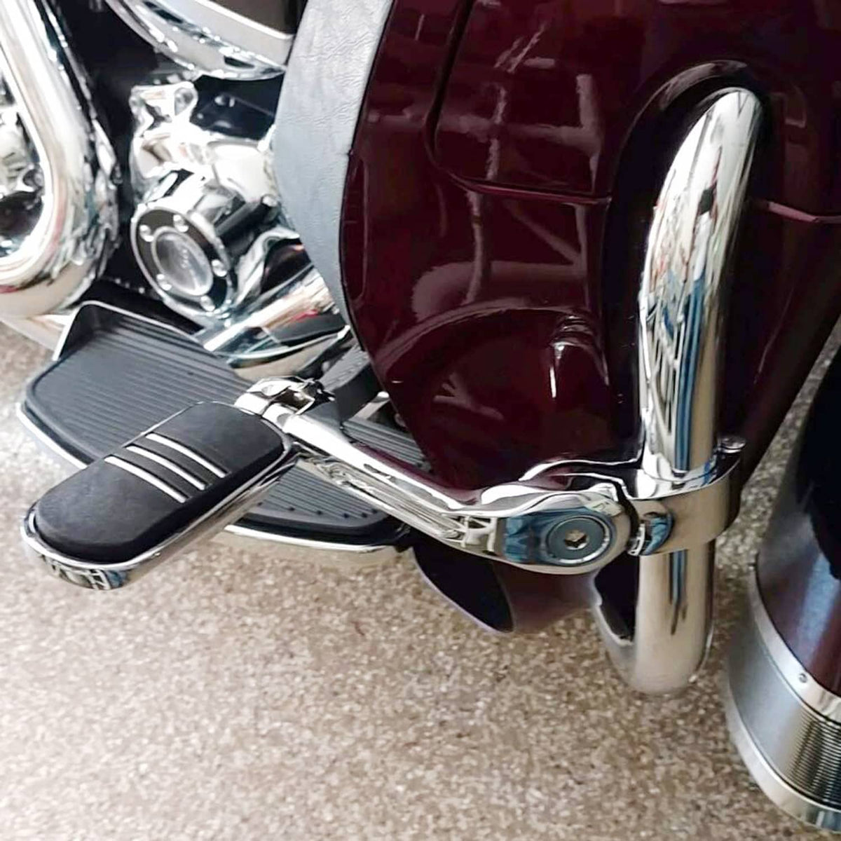Installed motorcycle highway foot pegs with chrome arms and black grooved pads