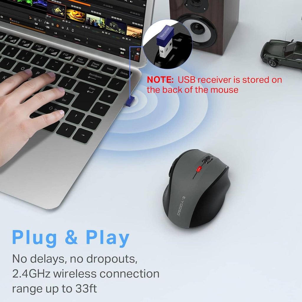 Gray wireless mouse with USB receiver stored on the back, beside a keyboard