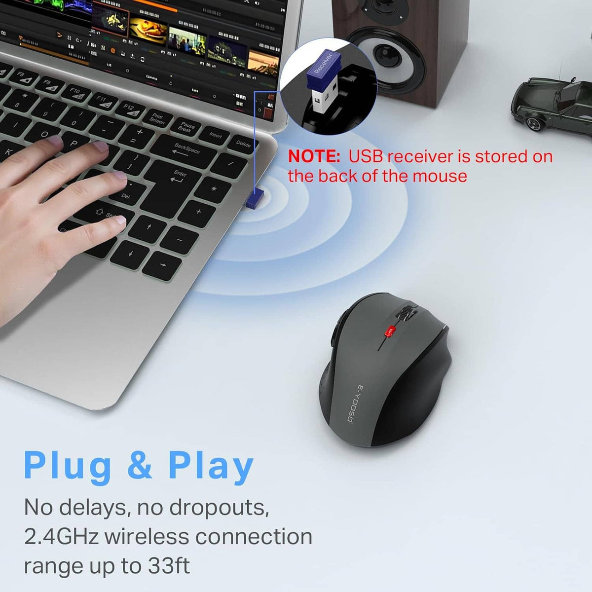 Gray wireless mouse with USB receiver stored on the back, beside a keyboard