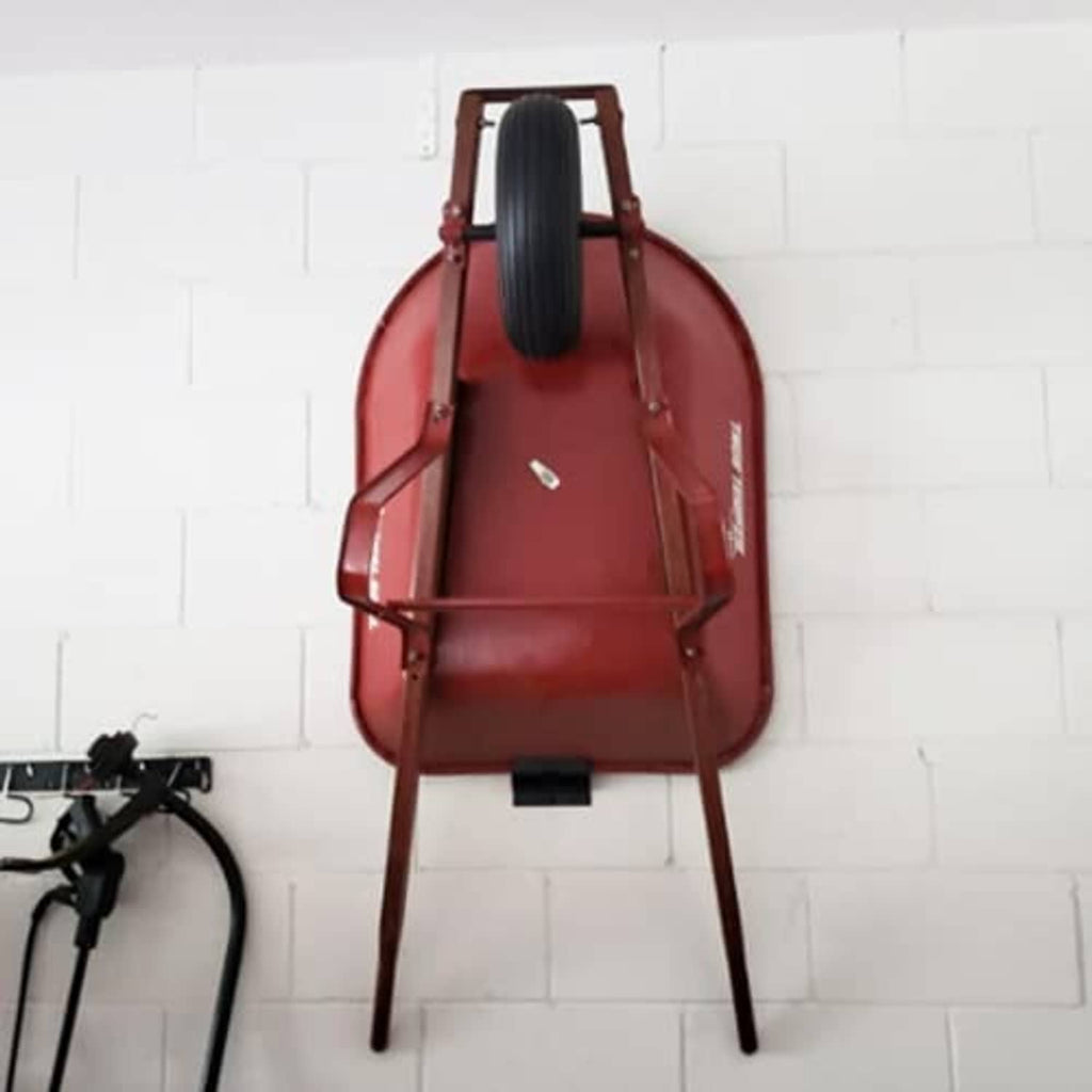 Red ladder stand accessory mounted to wall with arched frame and handles