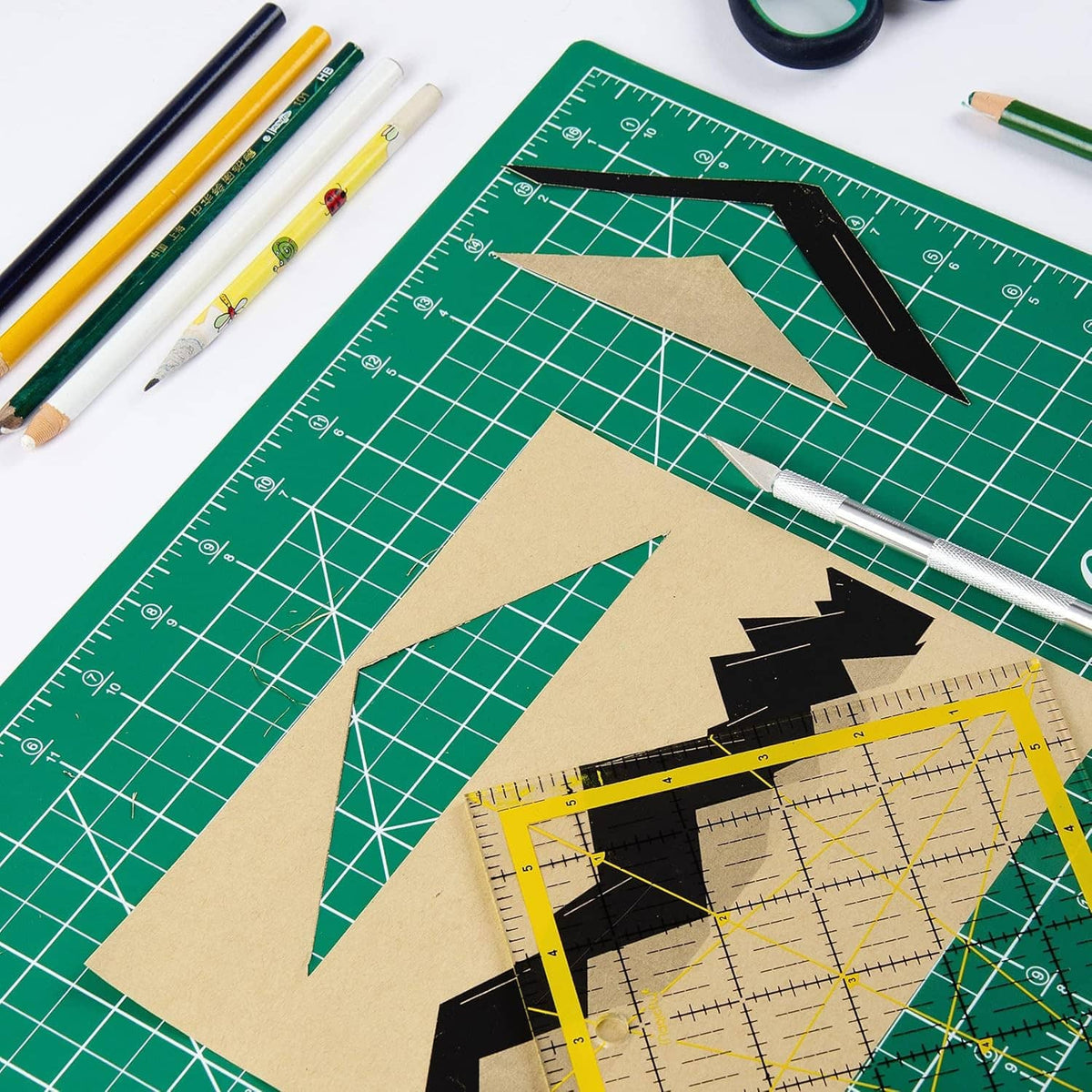 Green gridded cutting mat with scissors, markers, and craft template pieces on top
