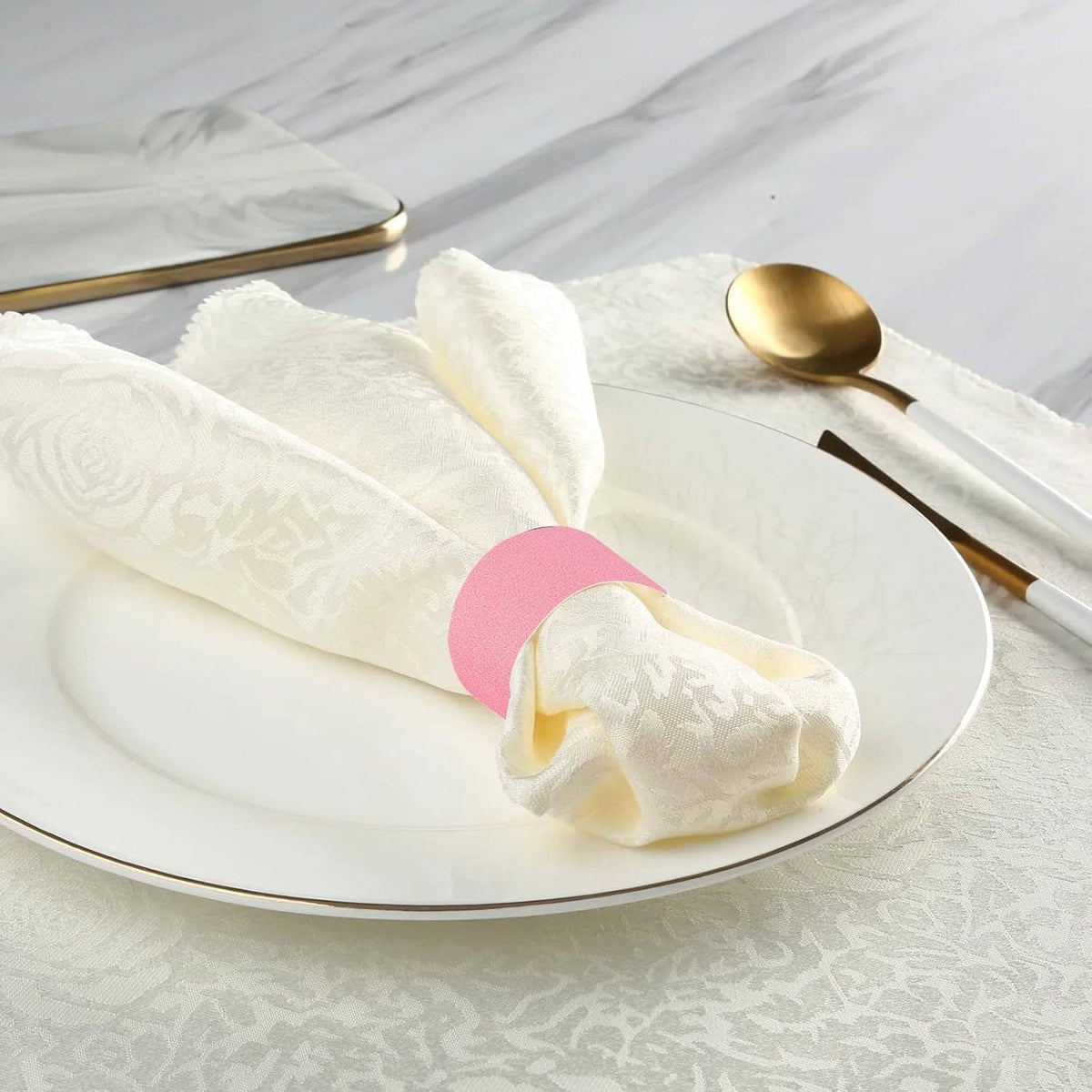 Pink adhesive napkin band holding white-wrapped cutlery on a plate