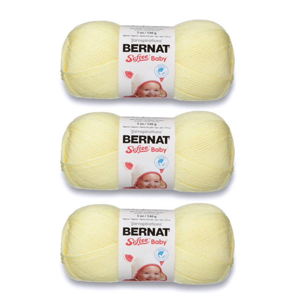 Three pale yellow baby yarn skeins with BERNAT Softee Baby labels