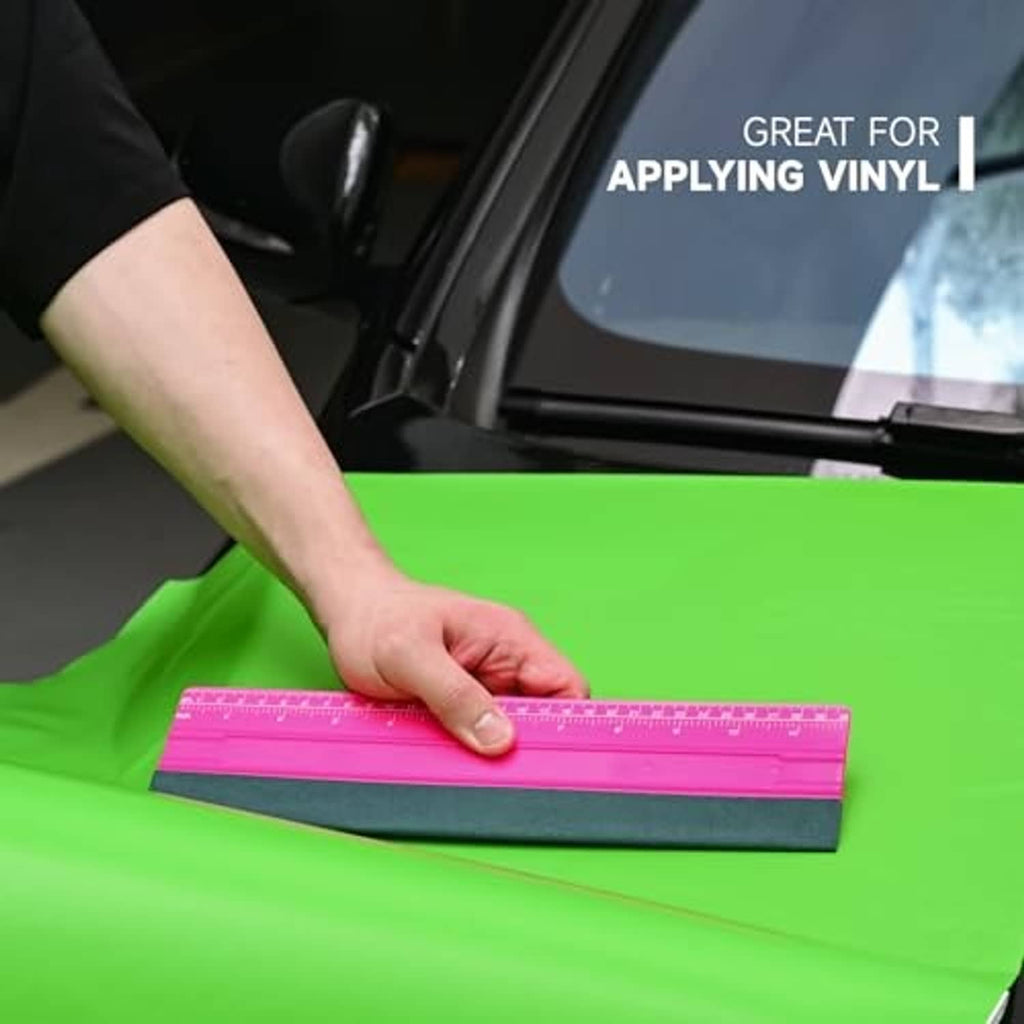 Pink squeegee with teal felt used to smooth vinyl film on a surface