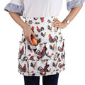 White chicken-printed egg apron with ruffled top and front skirt pockets holding one egg