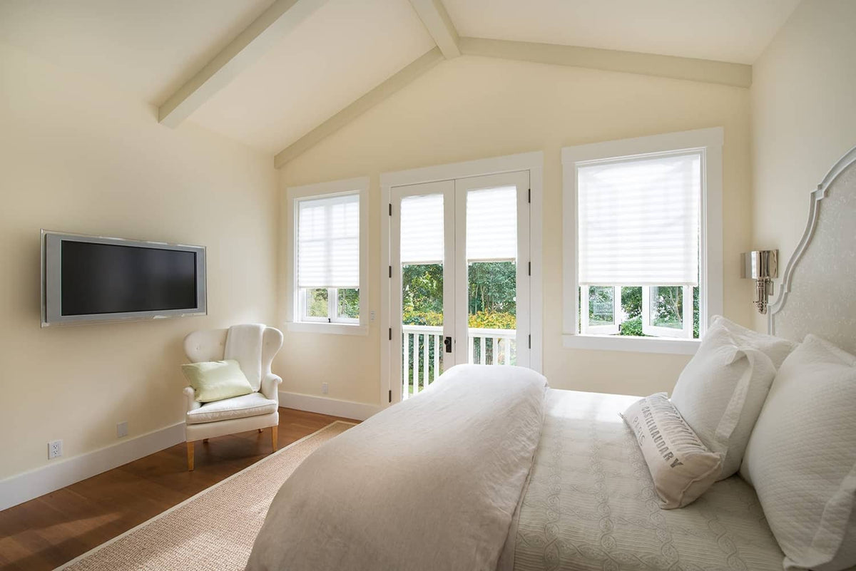 White pleated paper window shades over three windows in a bedroom