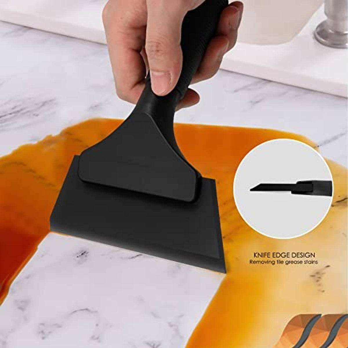 Handheld black rubber squeegee scraping orange cleaning fluid from glass