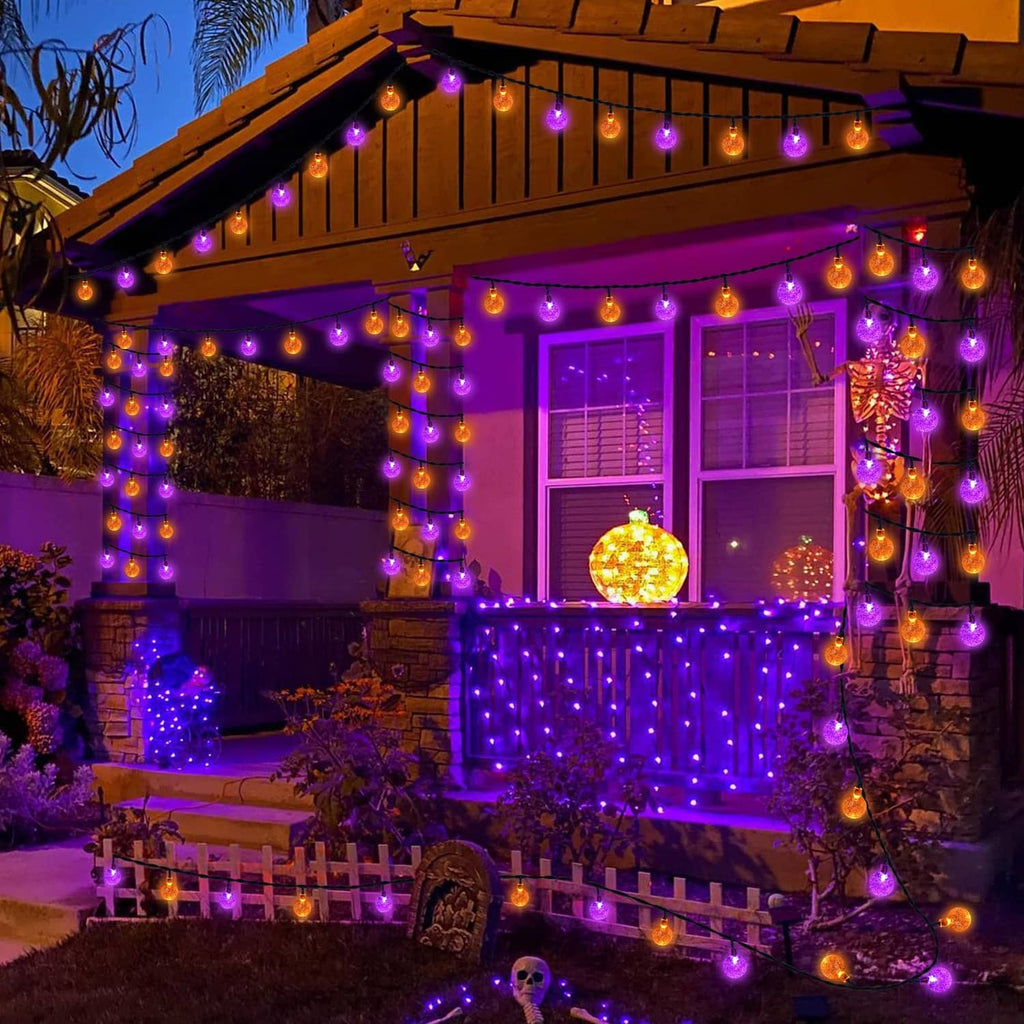 Halloween solar string lights across a porch roofline with orange and purple glowing globes.