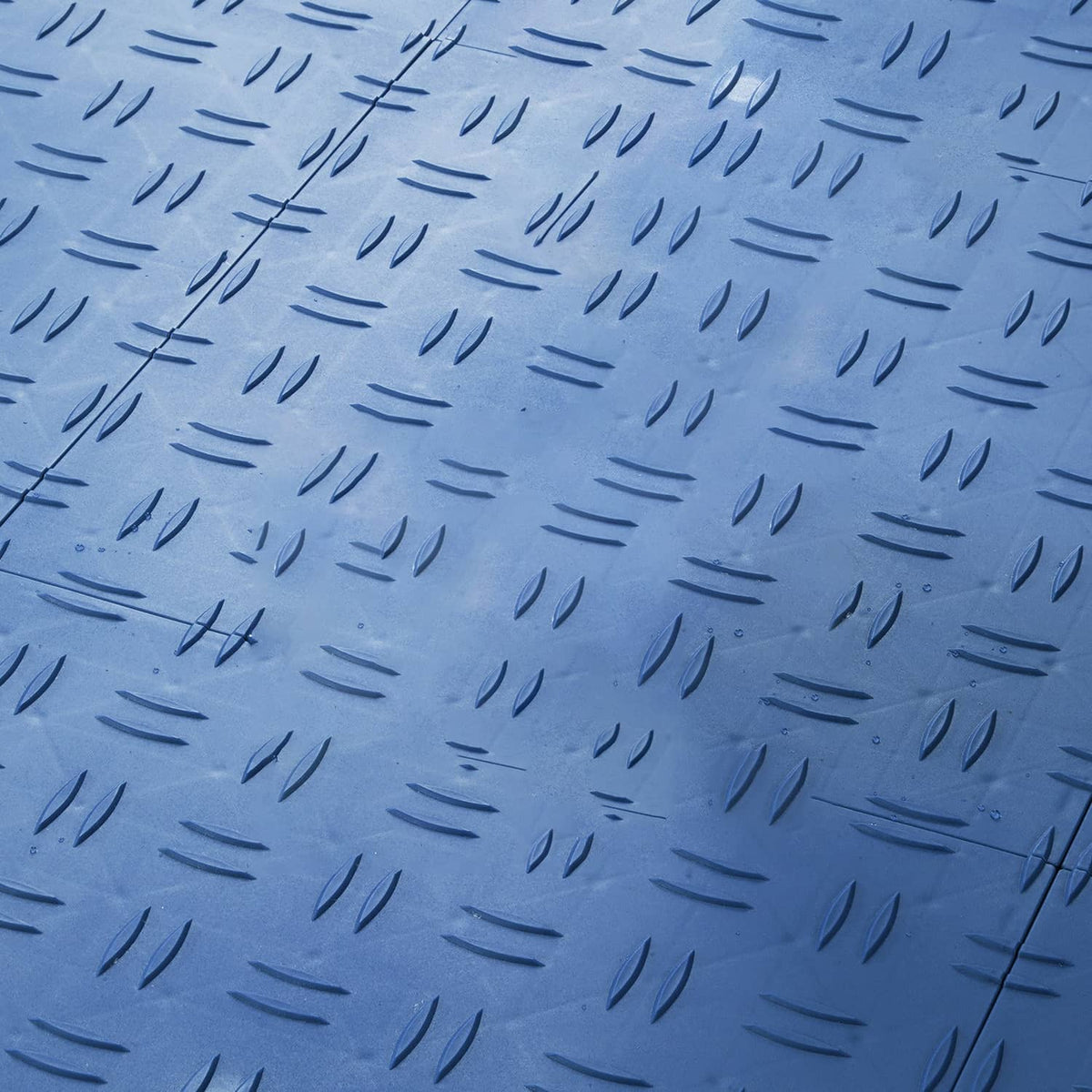 Blue garage floor tile close-up with raised anti-slip dash texture pattern