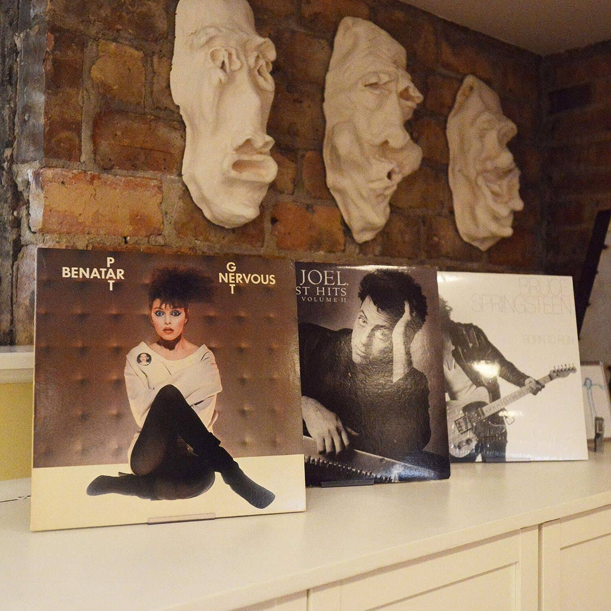 Wall-mounted album display frames holding vinyl record covers on a shelf