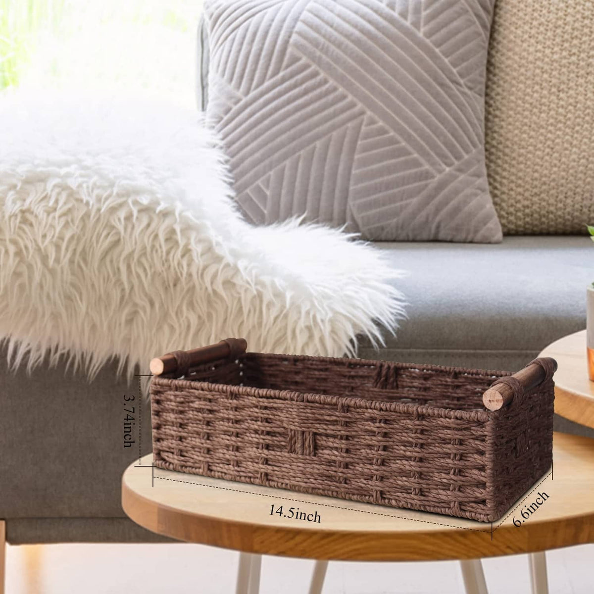 Brown woven storage basket with rolled rim and side handles on a couch table