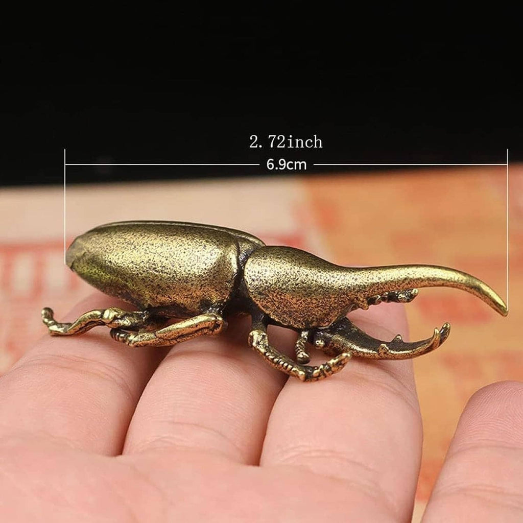 Miniature brass longhorn beetle ornament with long antennae, held in a hand