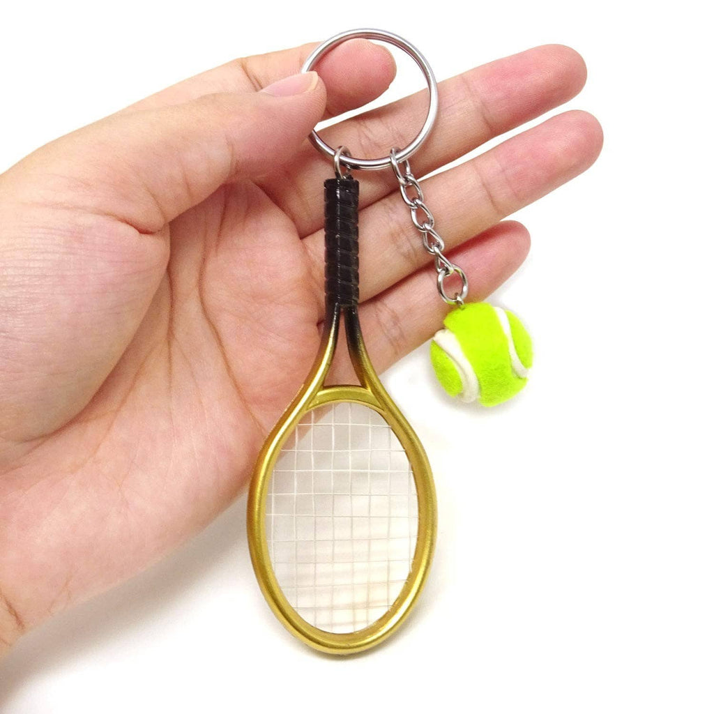 Mini tennis racket keychain held in hand: gold racket, black grip, green tennis ball charm