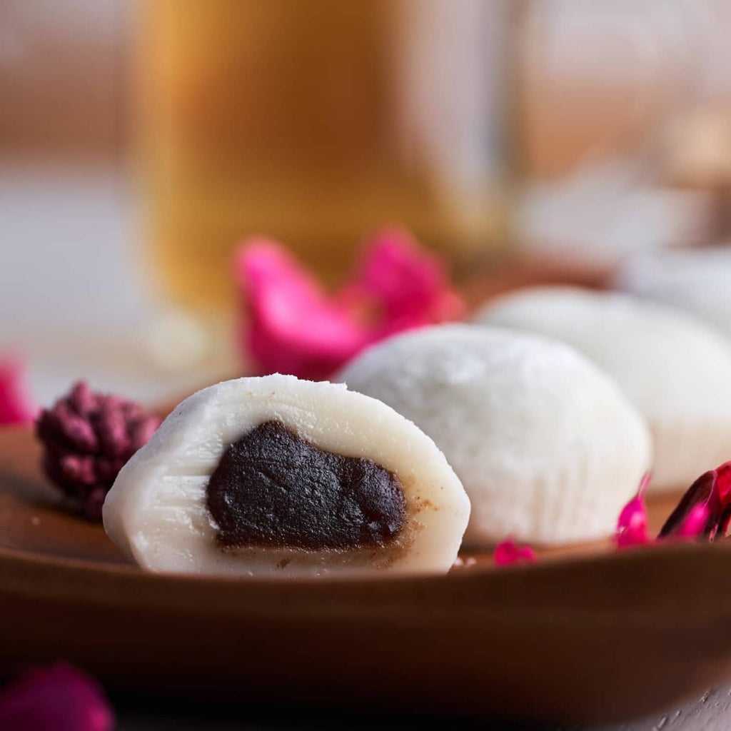 Half-moon mochi rice cake with dark filling on wooden tray