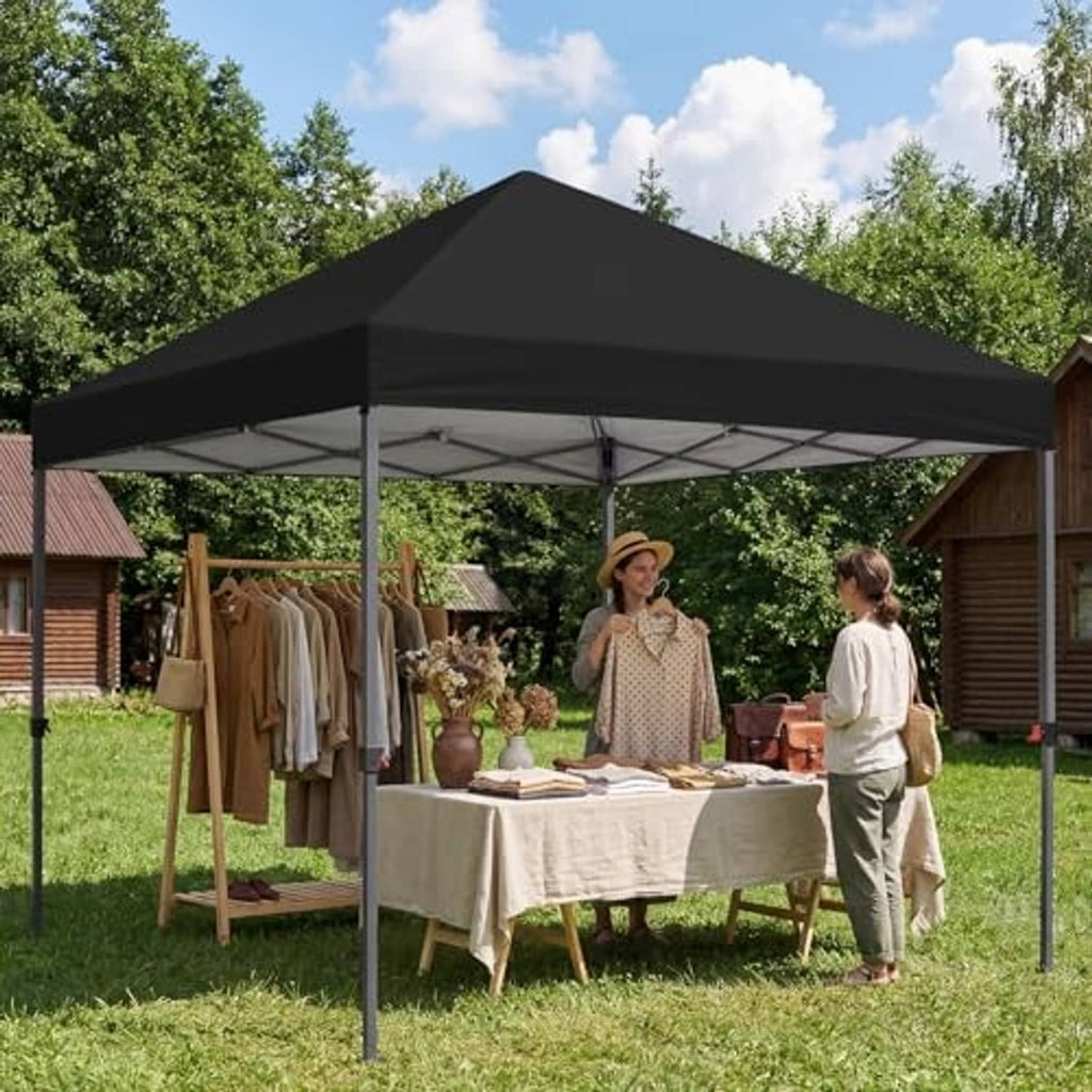 Black pop-up canopy top cover over an outdoor market table on grass