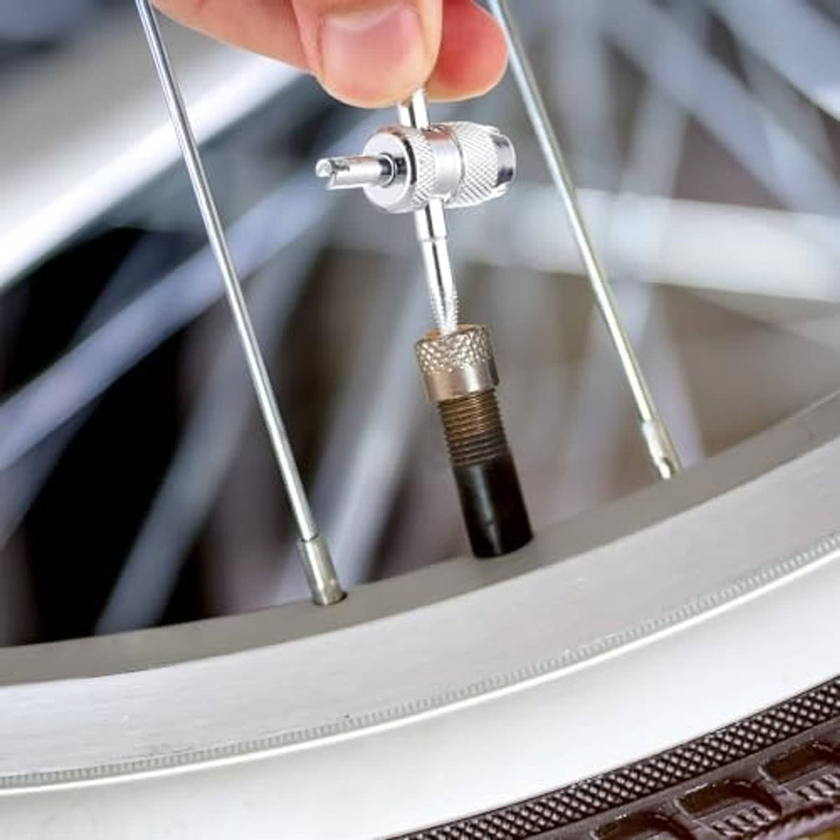 Metal valve core removal tool attached to a tire valve stem, ready to adjust