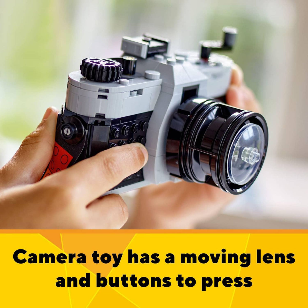 LEGO retro camera toy with moving lens and pressable buttons, in hands