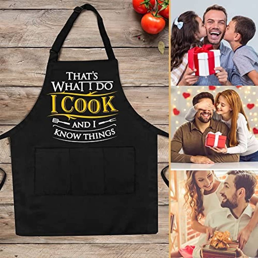Black apron laid flat with cross-back straps, large pocket, and 'I Cook' chest print