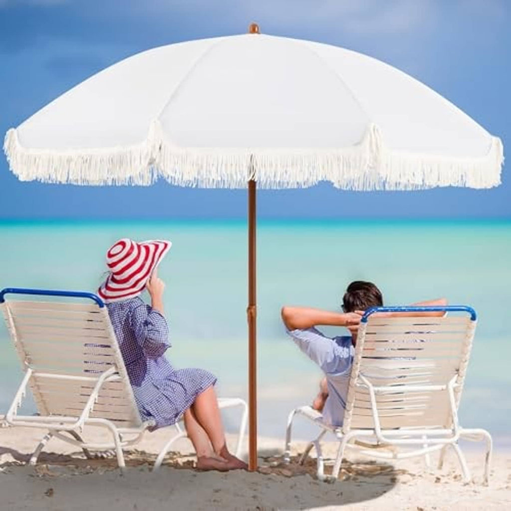 Cream patio umbrella fully opened with white fringe edge and wooden pole