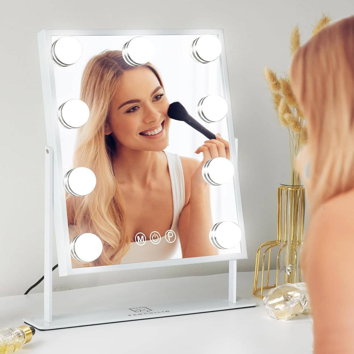 LED Hollywood makeup mirror with glowing bulbs, person applying makeup in reflection