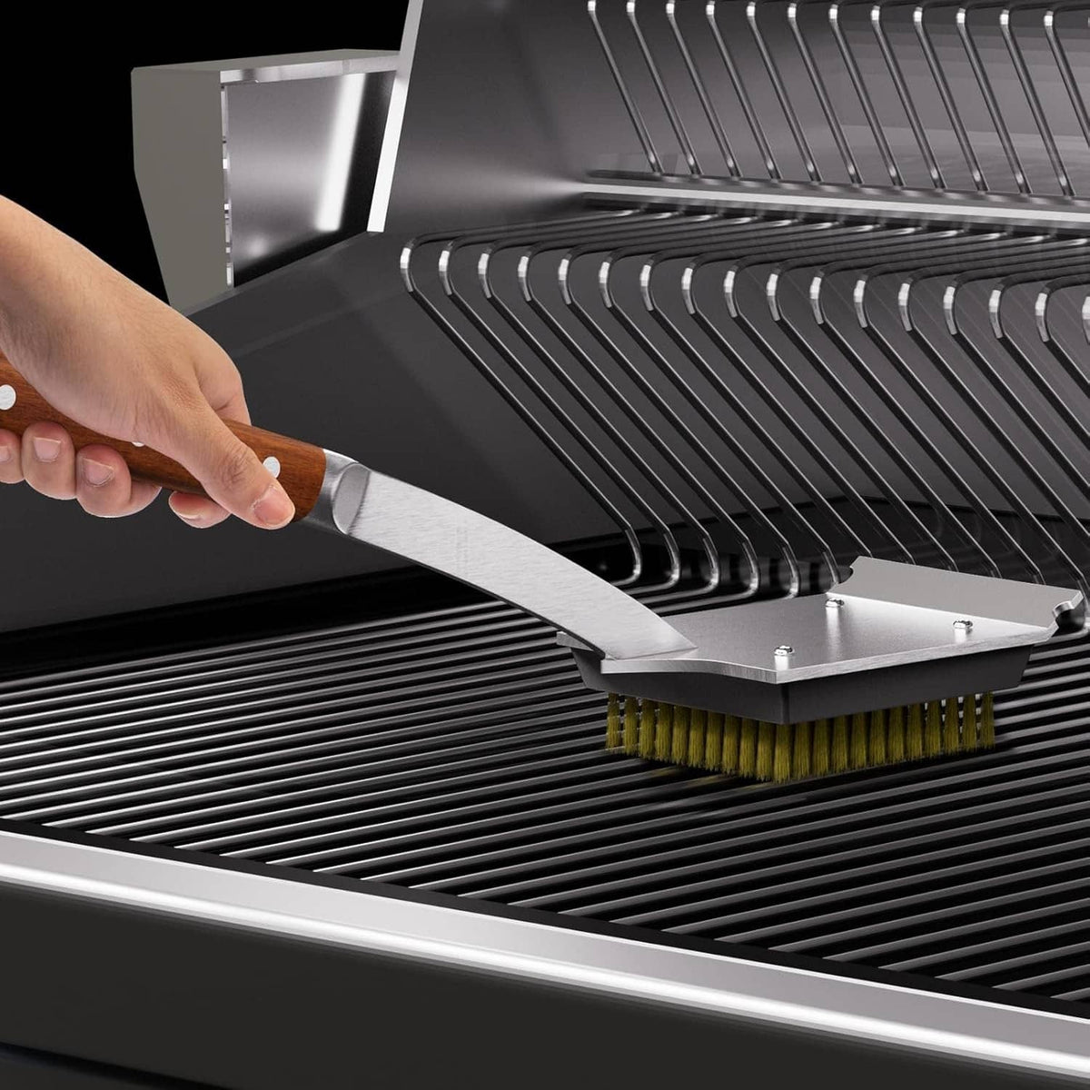 Hand using a grill brush with copper wire bristles on the cooking grate