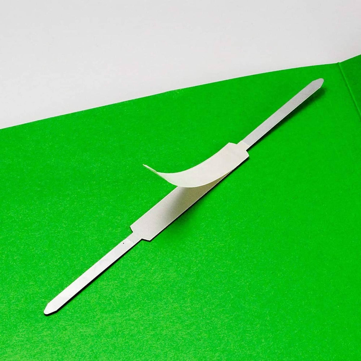 Self-adhesive prong paper fastener strips inserted along a paper edge