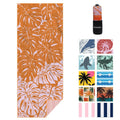 Orange beach towel with white palm leaf print, folded and in a zip pouch.