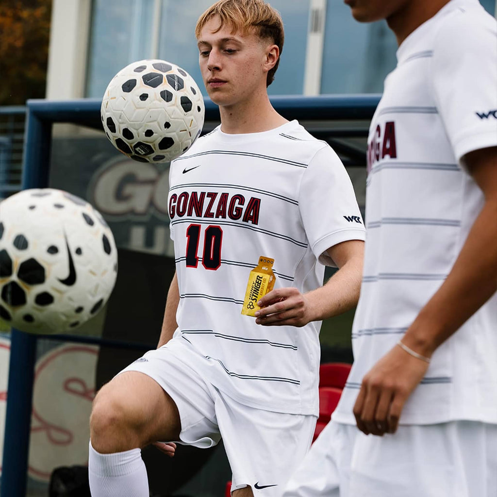 Honey Stinger energy gel packet held by an athlete in a white soccer jersey