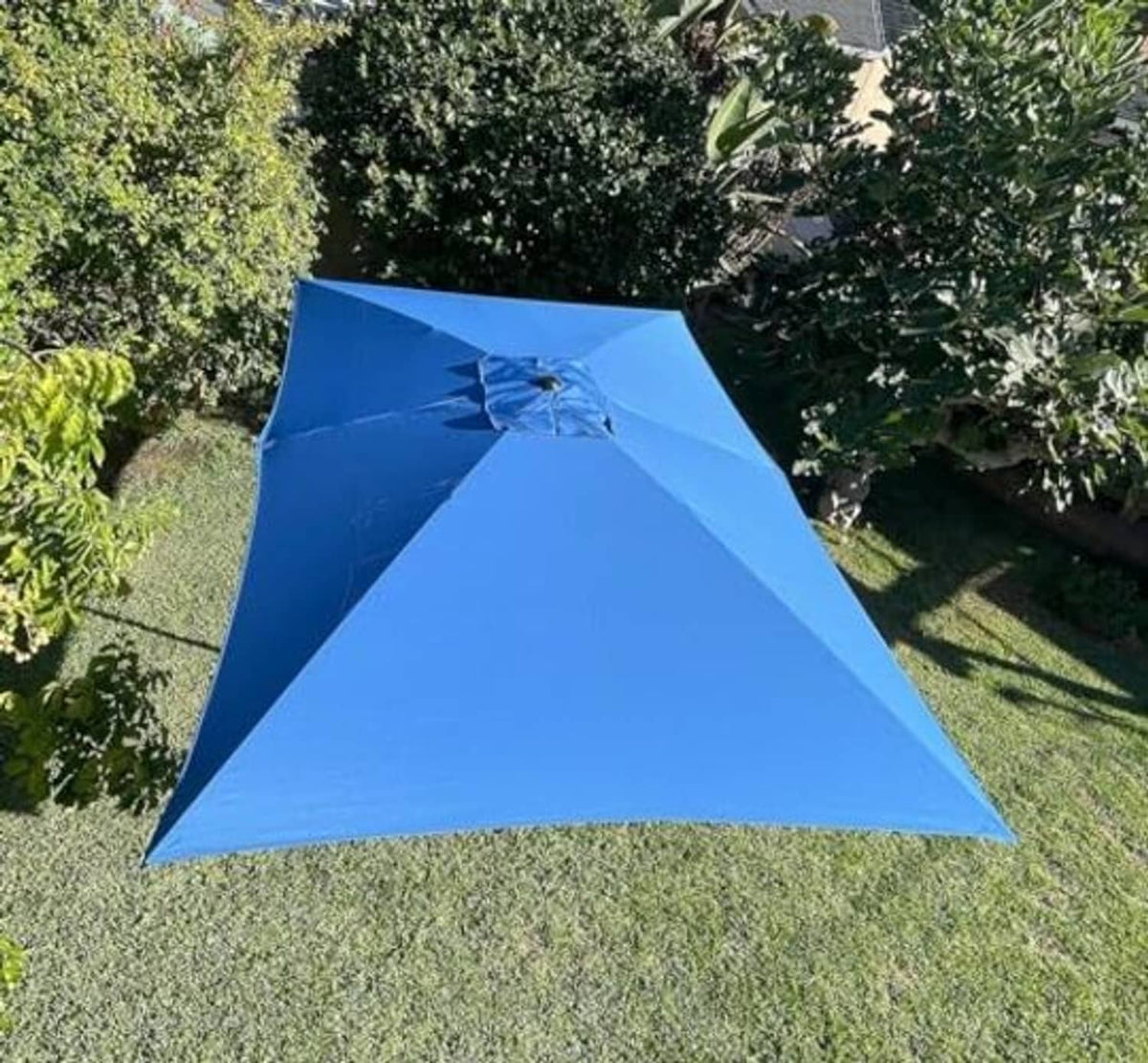 Blue rectangular replacement umbrella canopy in garden, with center button and rib seams.