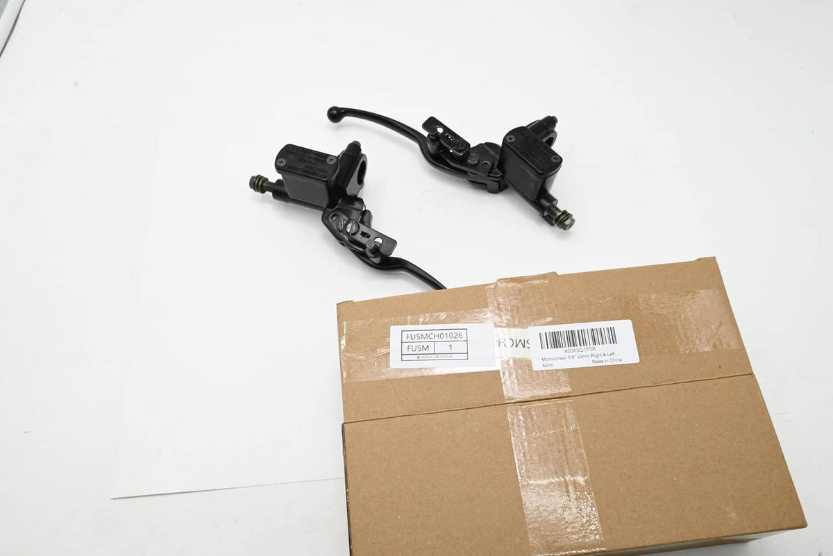 Brake master cylinder parts in box: black levers and cylinders with mounting hardware