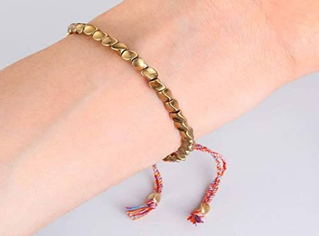 Gold-tone oval beaded bracelet with red braided tassels on wrist