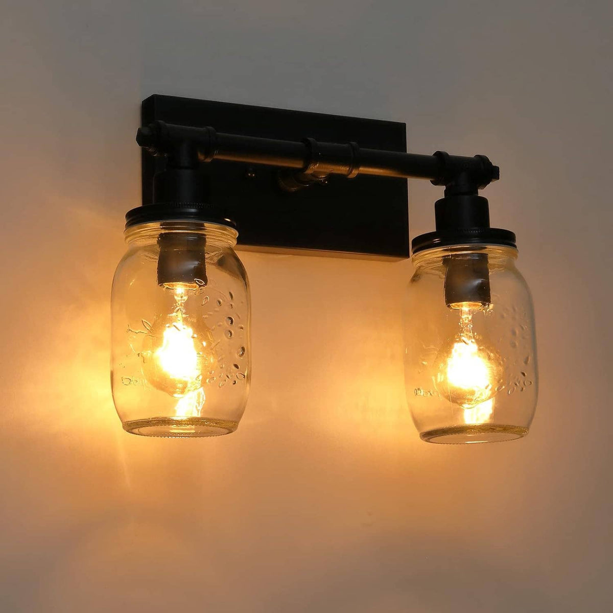 Black 2-light vanity light with two lit clear mason-jar shades on metal bar