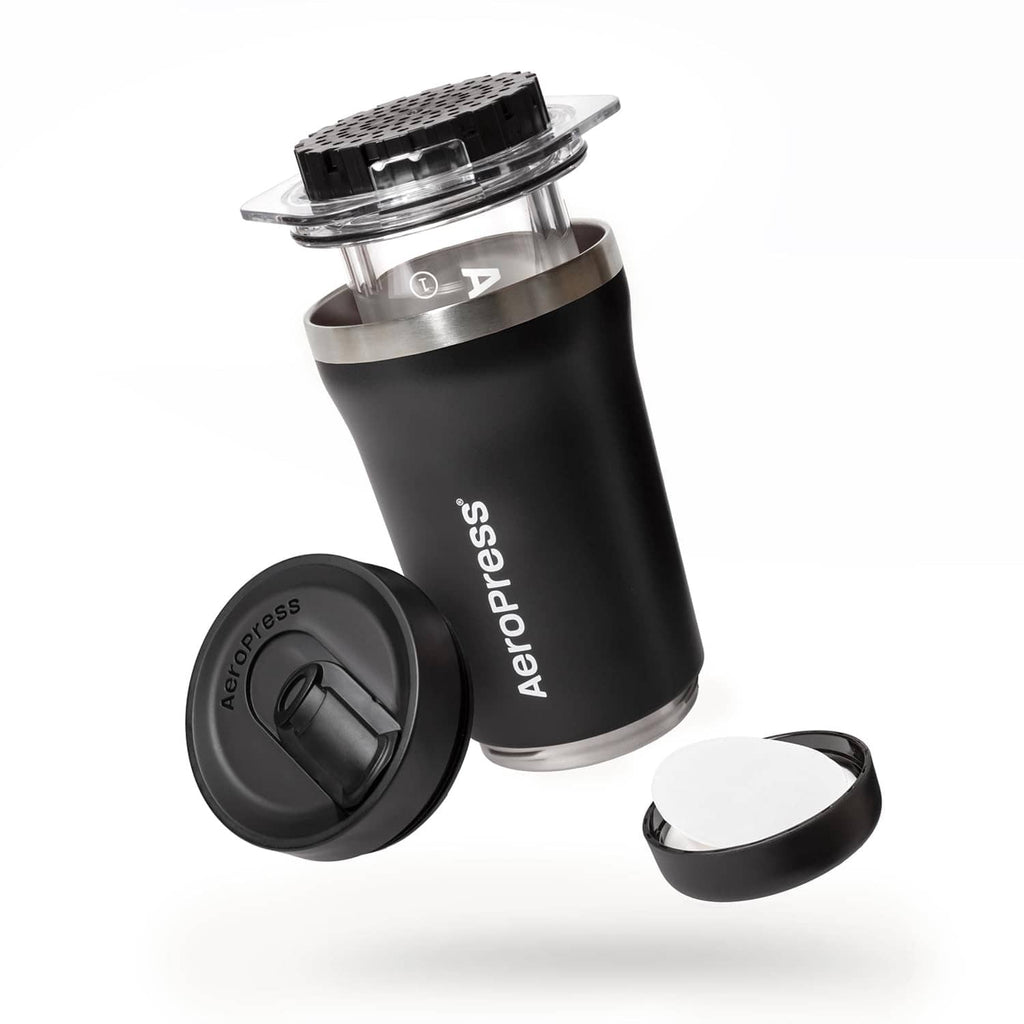 Black AeroPress coffee maker body with clear brewing top and detachable lid parts.