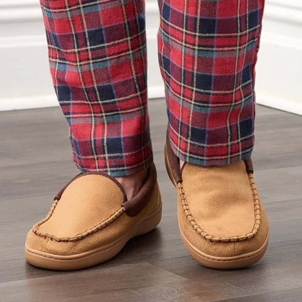 Tan slip-on slippers on wood floor with plaid pants cuffs above the openings