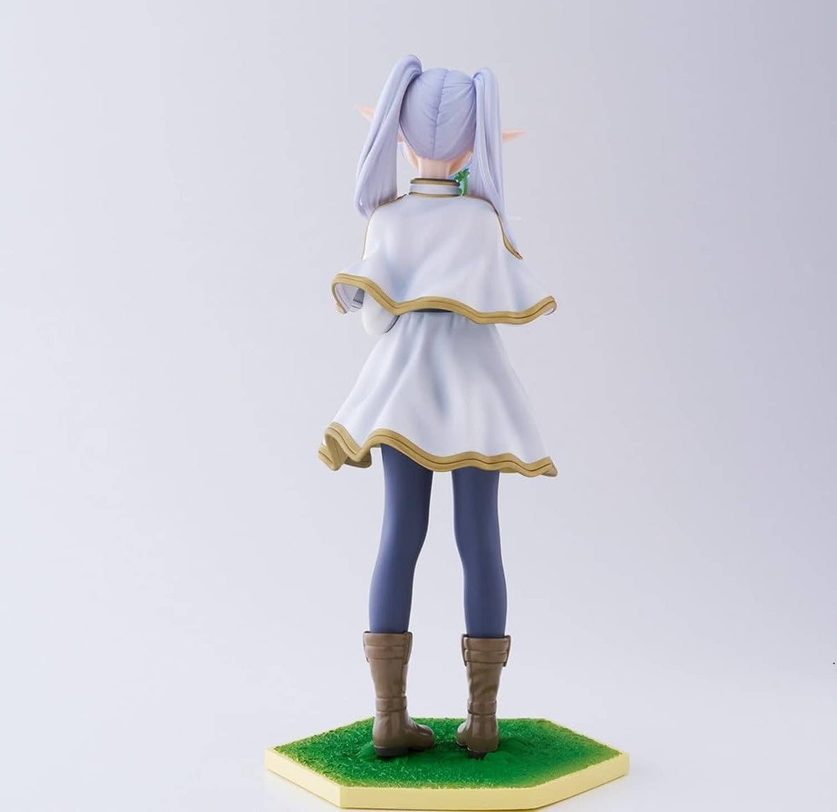 Back-view character figurine with lavender ponytail, white dress with gold trim, green base.