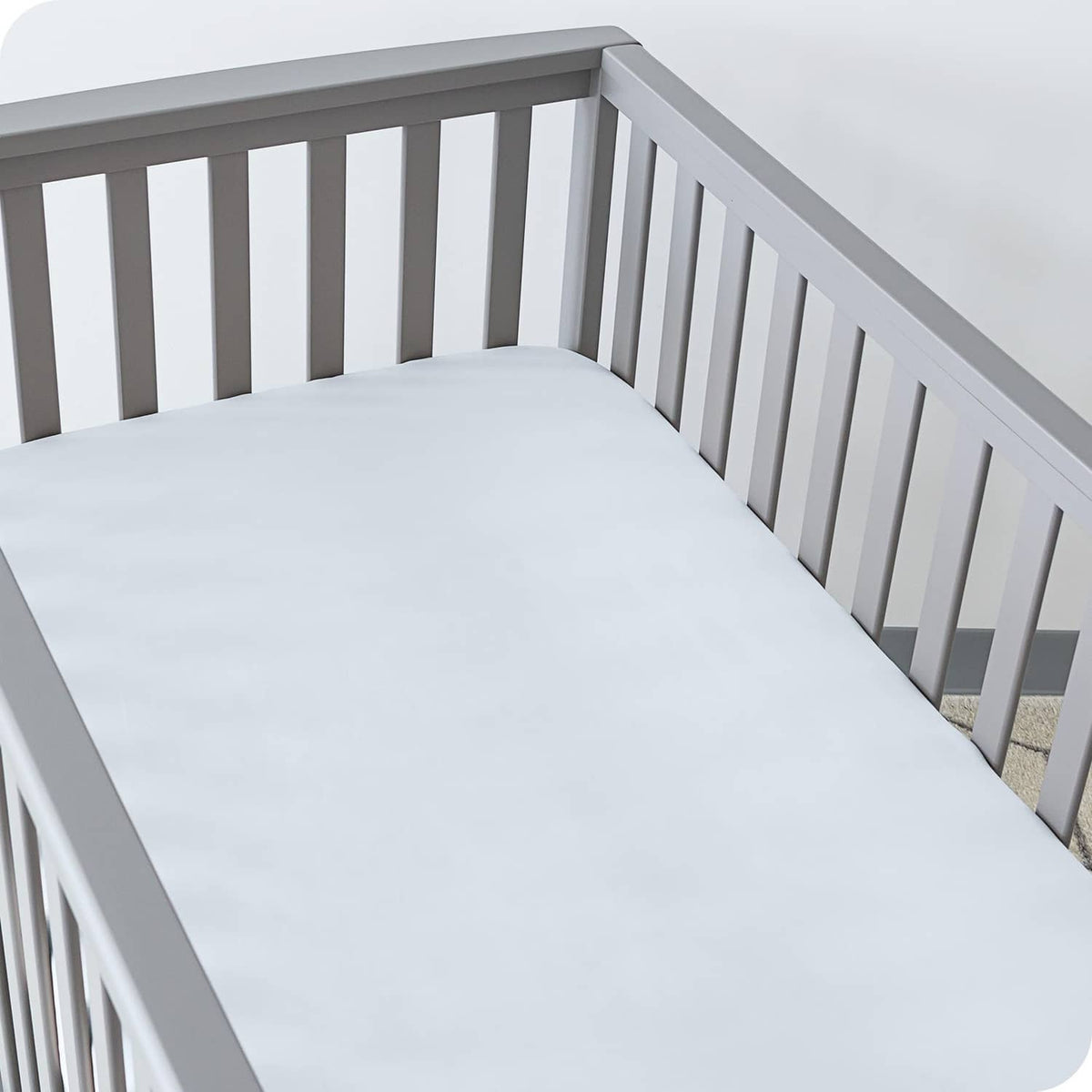 Light sky blue fitted crib sheet covering the mattress base in the crib