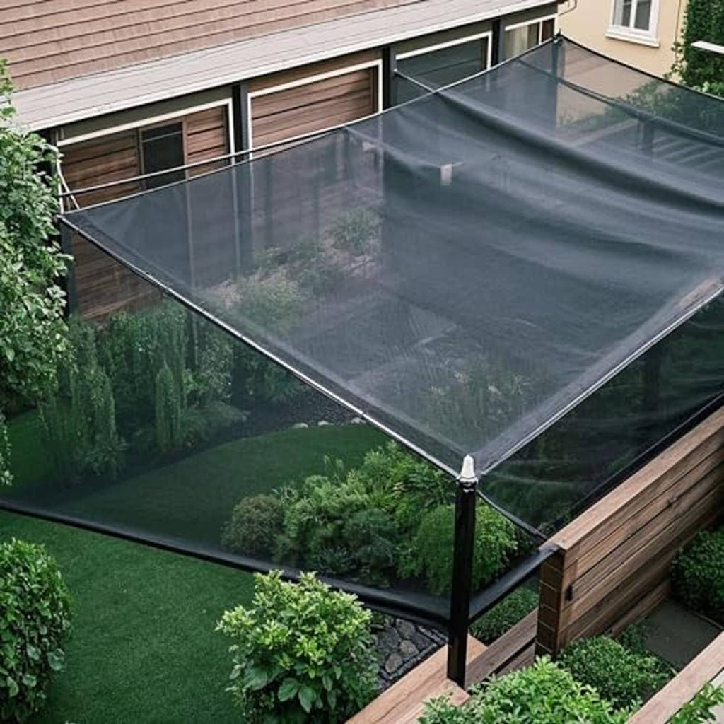 Black shade cloth mesh tarp installed over a backyard area with corner ties.