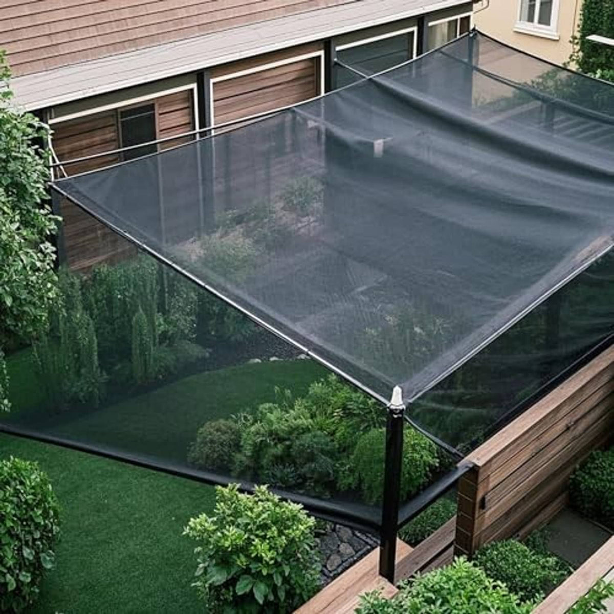 Black shade cloth mesh tarp installed over a backyard area with corner ties.