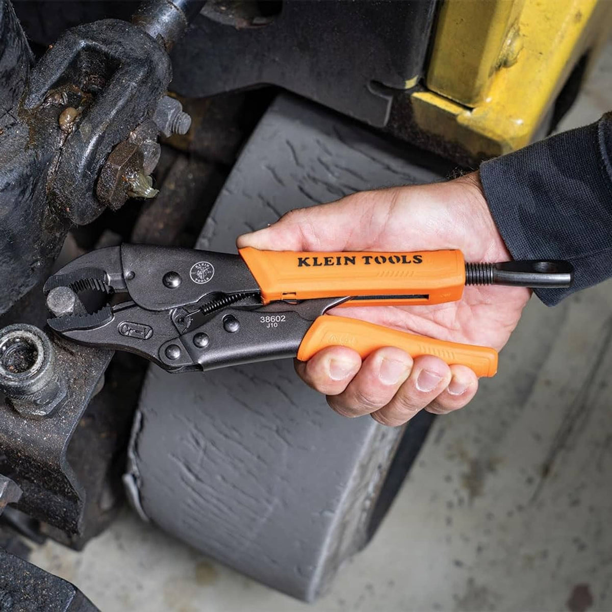 Orange-and-black locking pliers gripping a metal fitting near hoses