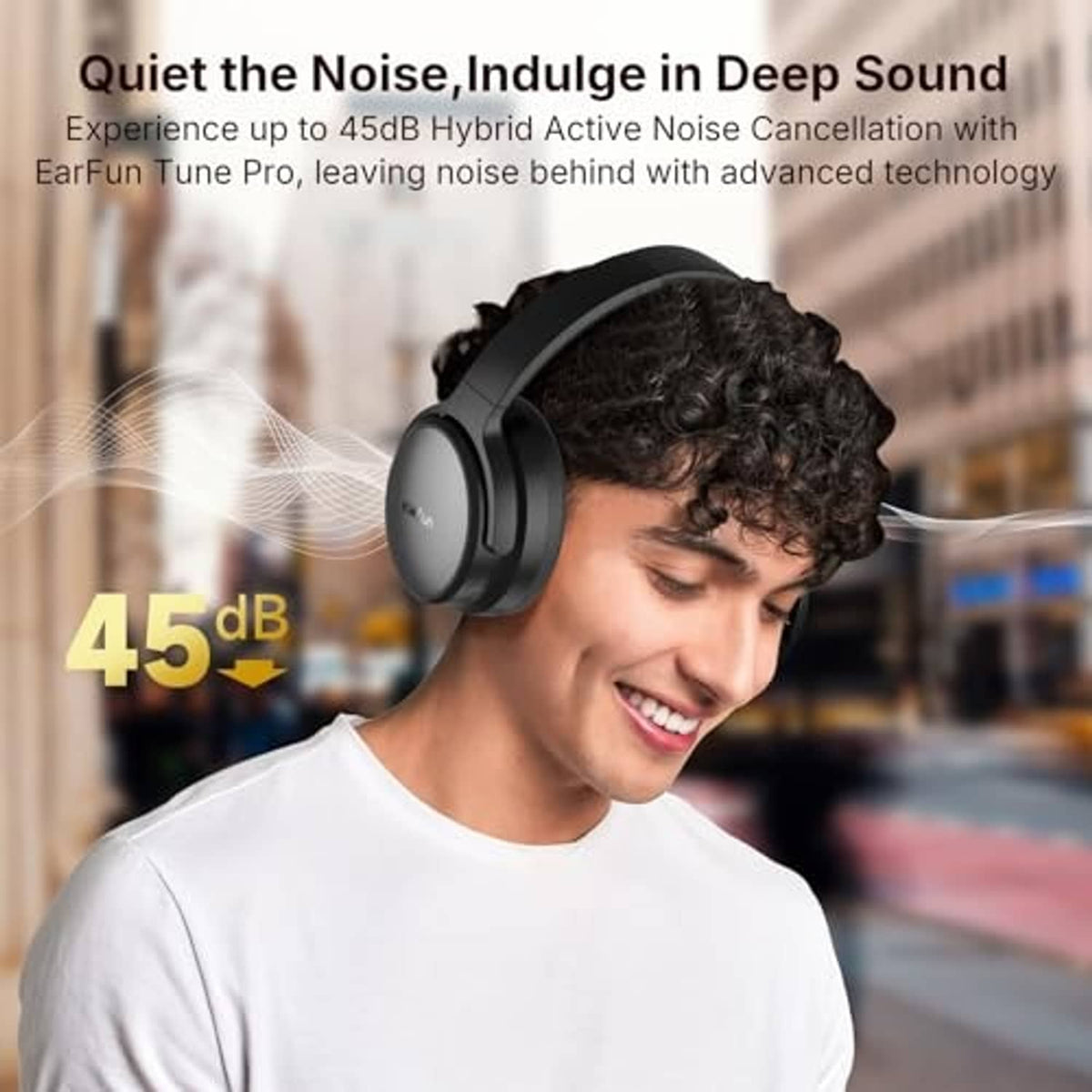 Black over-ear headphones worn by a smiling person in a white shirt.